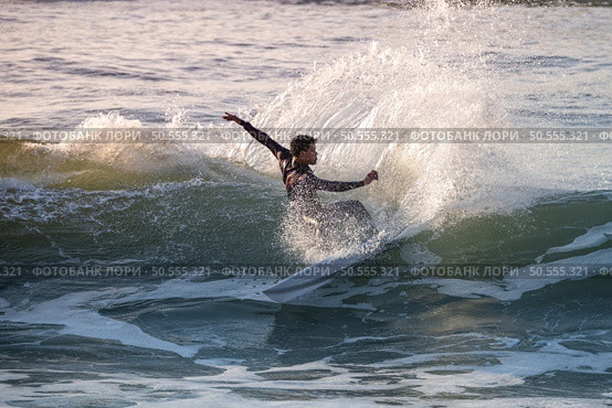Brave teenager making tricks on the rough sea during sunset. Стоковое фото, агентство Ingram Publishing / Фотобанк Лори