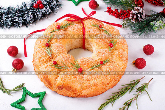 Bread Christmas wreath with cheese topped with rosemary and red berries on the white table. Festive monkey bread. Стоковое фото, фотограф Оксана Чаюн / Фотобанк Лори