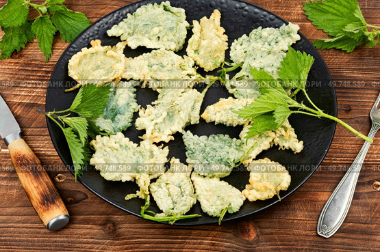 Breaded stinging nettles leaves on rustic wooden table. Hot spring greens appetizer. Breaded young nettle, vegetarian food . Стоковое фото, агентство Ingram Publishing / Фотобанк Лори