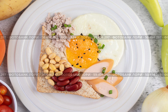 Breakfast consists of fried eggs, sausage, minced pork, bread, red beans and soy on a white plate. Стоковое фото, агентство Ingram Publishing / Фотобанк Лори