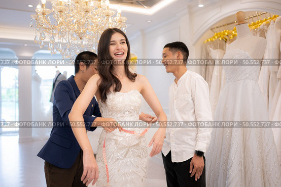 Bridal gown designers and tailors measure the size of the gown against the bride’s figure when she comes to try on the gown in order to make it perfect and ready to wear on the wedding day. Стоковое фото, агентство Ingram Publishing / Фотобанк Лори