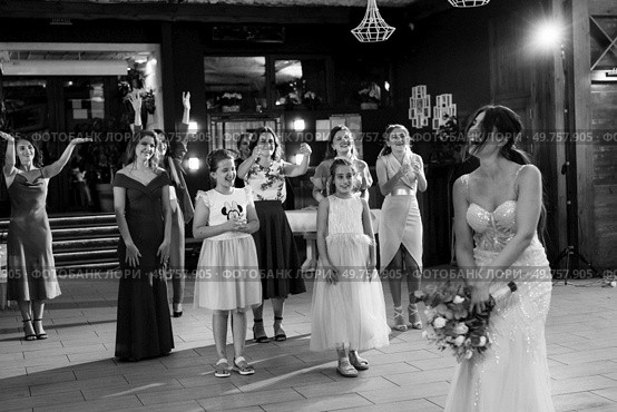 bride in a white dress throws a wedding bouquet to her unmarried girlfriends. Стоковое фото, агентство Ingram Publishing / Фотобанк Лори