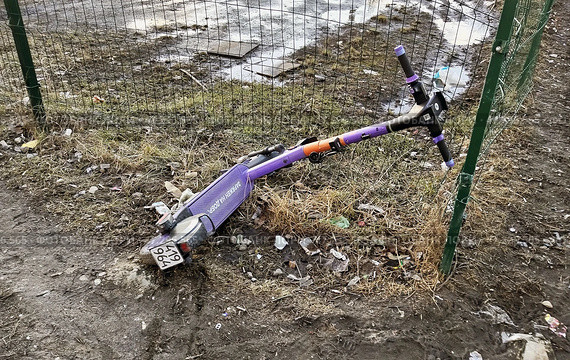 Брошенный электросамокат, на котором врезались в сварной забор из прутьев и повредили его. Редакционное фото, фотограф Александр Замараев / Фотобанк Лори
