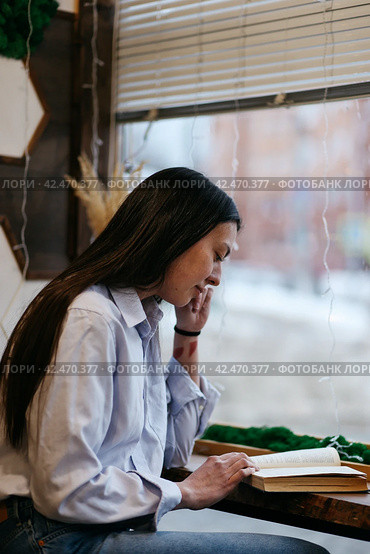 Brunette girl in a cafe drinking coffee, reading a book. Стоковое фото, фотограф Александра Баранова / Фотобанк Лори
