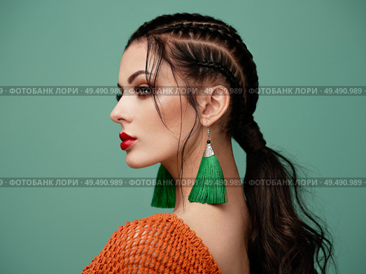 Brunette girl with perfect makeup. Beautiful model woman with curly hairstyle. Care and beauty hair products. Lady with braided hair. Model with jewelry. Turquoise background. Стоковое фото, агентство Ingram Publishing / Фотобанк Лори