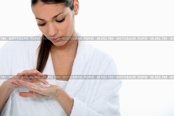Brunette wearing dressing gown applying hand cream. Стоковое фото, агентство Ingram Publishing / Фотобанк Лори