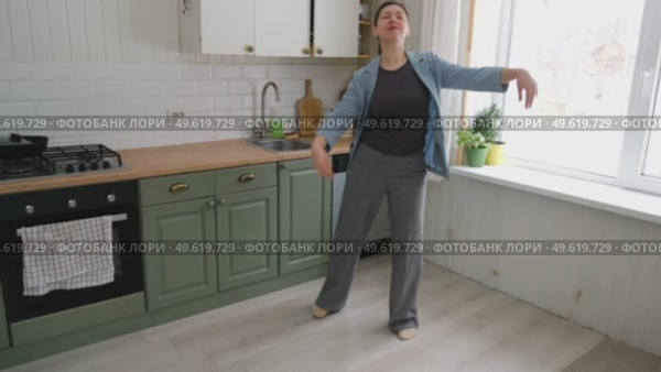 Brunette woman dance, have fun at home listens song, moves to music, feels overjoyed, celebrate good news, relish carefree life looks happy. Young adult female twirls, grooves. Lady dancing in kitchen. Стоковое видео, видеограф Марина Демидюк / Фотобанк Лори