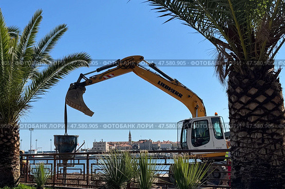 Budva,Montenegro-April 11,2025:A Liebherr excavator working by the sea. Редакционное фото, фотограф Margarita Davchenko / Фотобанк Лори