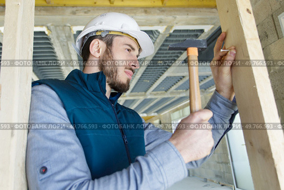 builder banging nail into wood with a hammer. Стоковое фото, агентство Ingram Publishing / Фотобанк Лори