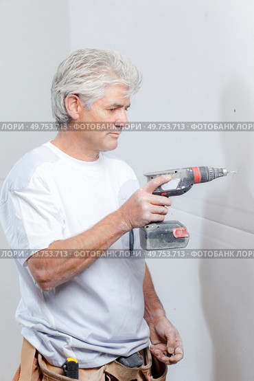 Builder drilling hole in wall. Стоковое фото, агентство Ingram Publishing / Фотобанк Лори