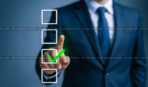 Business executive in blurred office environment touching glowing green check mark on virtual checklist, indicating positive outcome, completed objectives and effective strategy. Стоковое фото, фотограф Павел Муравьев / Фотобанк Лори