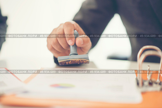 Business hand putting stamp on a document, close up. Стоковое фото, агентство Ingram Publishing / Фотобанк Лори