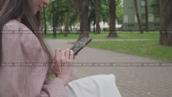 Business woman in the park in the summer writes a message on the phone. Стоковое видео, видеограф Громов Александр / Фотобанк Лори