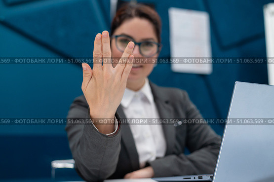 Business woman saying hello in Vulcan style while sitting at her desk in the office. Стоковое фото, фотограф Михаил Решетников / Фотобанк Лори