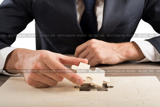 Businessman complete a puzzle inserting last piece. Complete a puzzle. Стоковое фото, агентство Ingram Publishing / Фотобанк Лори