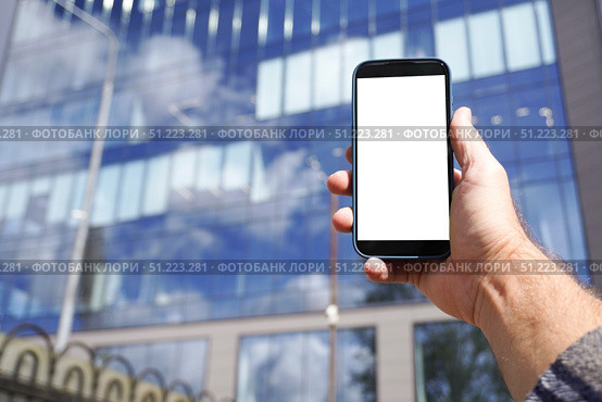 Businessman holding smartphone with blank screen in front of office building. Стоковое фото, фотограф Дмитрий Цветков / Фотобанк Лори