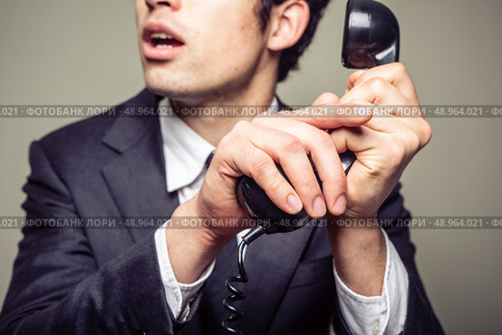 Businessman is covering the phone to speak in private to someone in the room. Стоковое фото, агентство Ingram Publishing / Фотобанк Лори