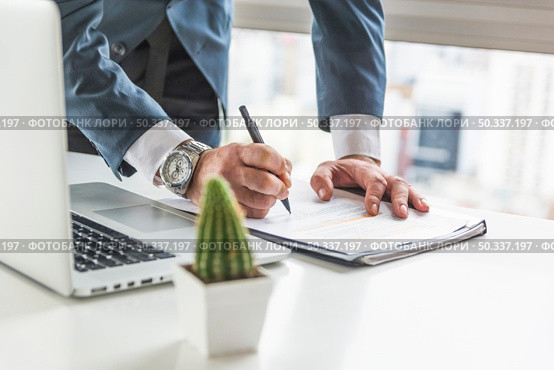 businessman writing document with pen desk with laptop. Стоковое фото, агентство Ingram Publishing / Фотобанк Лори