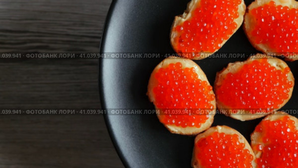 Бутерброды с красной икрой на чёрной тарелке. Съёмка с вращением. Стоковое видео, видеограф Евгений Ковальский / Фотобанк Лори