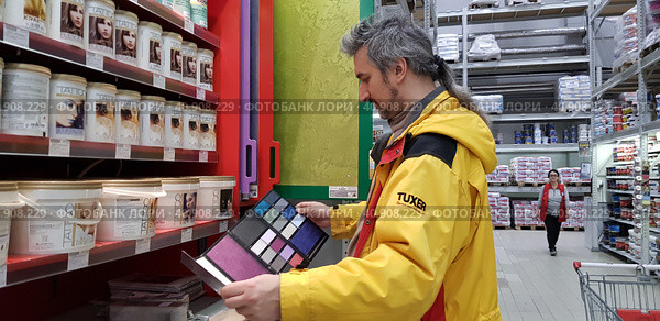 Buyer selects paint and plaster in the store (2018 год). Редакционное фото, фотограф Анна Кривицкая / Фотобанк Лори