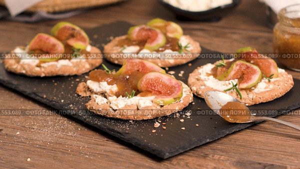 Canape or crostini with multigrain  crispread with cream cheese and fig jam on a slate board. Delicious appetizer ideal as an aperitif. Стоковое фото, агентство Ingram Publishing / Фотобанк Лори
