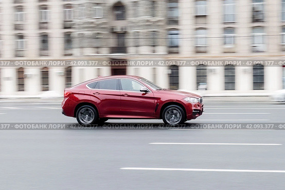 Car BMW X6 F16 moving on the street. SUV vehicle driving along sunny street in city with blurred background. Редакционное фото, фотограф Константин Григорьев / Фотобанк Лори