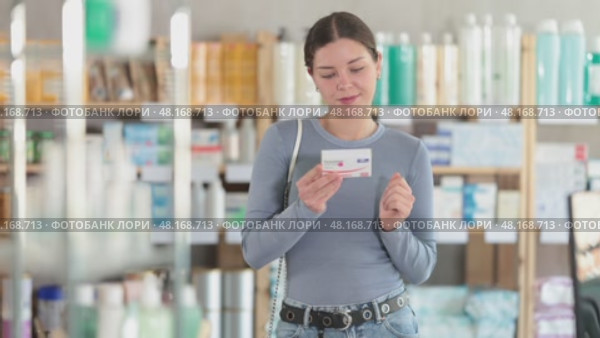 Careful young woman holding pills of paracetamol for purchase in drugstore. Стоковое видео, видеограф Яков Филимонов / Фотобанк Лори