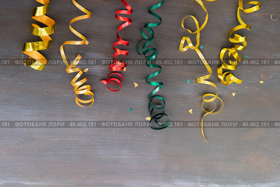 Carnaval festive curling paper decorations on dark wooden background. Carnaval decorations on dark wooden background. Стоковое фото, агентство Ingram Publishing / Фотобанк Лори
