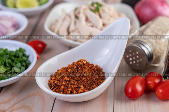 Cayenne chili in a white spoon, tomato placed on a wooden table. Selective focus. Стоковое фото, агентство Ingram Publishing / Фотобанк Лори