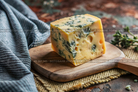 Cheese with mold, a slice of cheese with mold door blue or Roquefort on a cutting board. Delicious food. Стоковое AI-изображение, AI-художник Photojuli / Фотобанк Лори