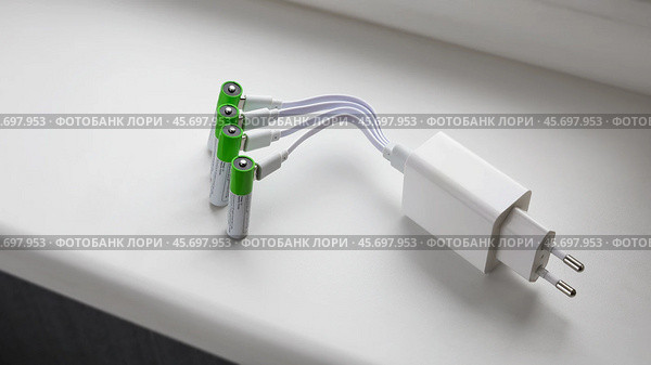 Четыре аккумуляторные батарейки ААА с подключенными штекерами USB проводов зарядки с блоком питания от розетки. Стоковое фото, фотограф Vladimir Vikhrov / Фотобанк Лори