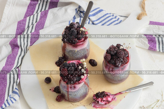 Chia pudding with blackberries, three portions in glass jars on a white table. Стоковое фото, агентство Ingram Publishing / Фотобанк Лори
