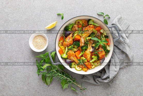 Chicken drumsticks roasted with vegetables in cast iron pan on kitchen table, top down view. Стоковое фото, агентство Ingram Publishing / Фотобанк Лори