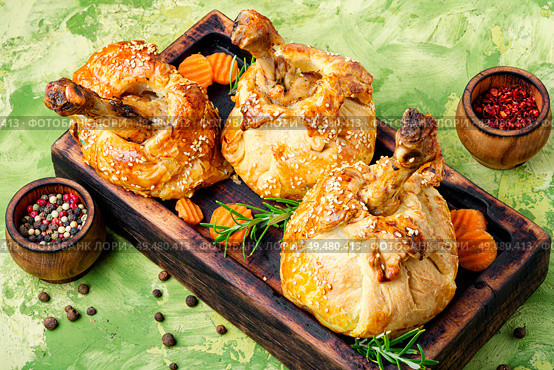 Chicken legs in pastry.Chicken leg in puff pastry on cutting board. Chicken drumstick baked in dough. Стоковое фото, агентство Ingram Publishing / Фотобанк Лори