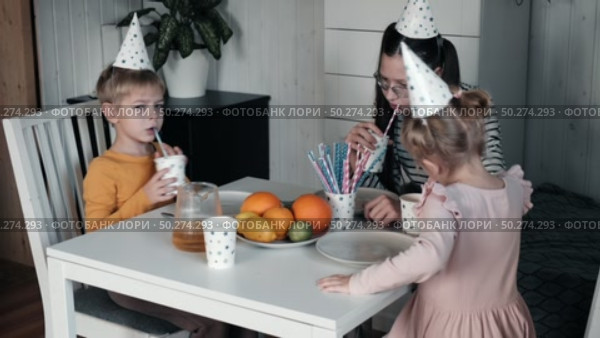 Children Drinking Juice on a Birthday Party at Home. Siblings, girls and a boy together celebrating a party, eating cake sitting at festive table. Little Kid Celebration. Surprise. Low key. Стоковое видео, видеограф Марина Демидюк / Фотобанк Лори