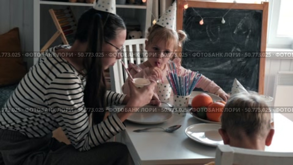 Children Drinking Juice on a Birthday Party at Home. Siblings, girls and a boy together celebrating a party, eating cake sitting at festive table. Little Kid Celebration. Surprise. Low key. Стоковое видео, видеограф Марина Демидюк / Фотобанк Лори