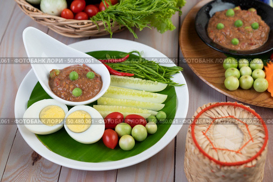 Chili paste paste in a bowl with eggplant, carrots, chili, cucumbers in a basket on wood table. Стоковое фото, агентство Ingram Publishing / Фотобанк Лори