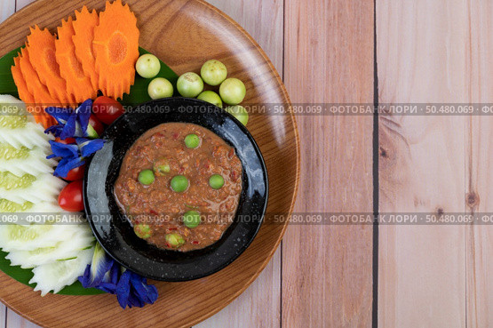 Chili paste paste in a bowl with eggplant, carrots, chili, cucumbers in a basket on wood table. Стоковое фото, агентство Ingram Publishing / Фотобанк Лори