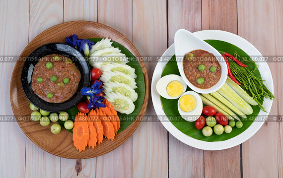 Chili paste paste in a bowl with eggplant, carrots, chili, cucumbers in a basket on wood table. Стоковое фото, агентство Ingram Publishing / Фотобанк Лори