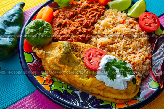 Chili relleno chili pepper poblano filled with cheese in dish with with rice and frijoles beans. Стоковое фото, агентство Ingram Publishing / Фотобанк Лори
