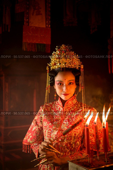Chinese woman make wishes, pray, and light candles. On the occasion of the annual Chinese New Year festival, in a revered shrine or temple, And in Chinese where candles mean good luck and happiness. Стоковое фото, агентство Ingram Publishing / Фотобанк Лори