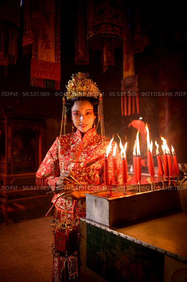 Chinese woman make wishes, pray, and light candles. On the occasion of the annual Chinese New Year festival, in a revered shrine or temple, And in Chinese where candles mean good luck and happiness. Стоковое фото, агентство Ingram Publishing / Фотобанк Лори