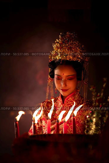 Chinese woman make wishes, pray, and light candles. On the occasion of the annual Chinese New Year festival, in a revered shrine or temple, And in Chinese where candles mean good luck and happiness. Стоковое фото, агентство Ingram Publishing / Фотобанк Лори