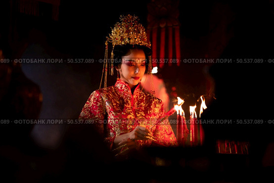 Chinese woman make wishes, pray, and light candles. On the occasion of the annual Chinese New Year festival, in a revered shrine or temple, And in Chinese where candles mean good luck and happiness. Стоковое фото, агентство Ingram Publishing / Фотобанк Лори