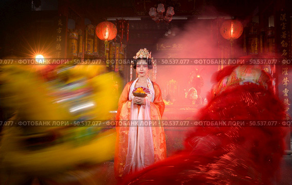 Chinese woman with yellow and red lions It is considered to enhance the prosperity for oneself on the occasion of the Chinese New Year festival every year and in Chinese, it means prosperous, fortunate, happy, prosperous. Стоковое фото, агентство Ingram Publishing / Фотобанк Лори