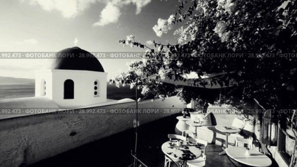 Church dome with wind playing with flower shrub on a terrace of traditional cafeteria in typical greek village of Oia, Santorini island, Greece. Стоковое видео, видеограф Matej Kastelic / Фотобанк Лори