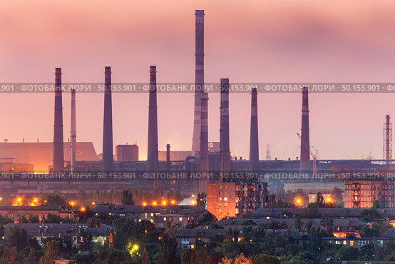 City buildings on the background of steel factory with smokestacks at night.  Metallurgical plant with chimney. steelworks, iron works. Heavy industry. Air pollution, smog. Industrial landscape. Стоковое фото, агентство Ingram Publishing / Фотобанк Лори