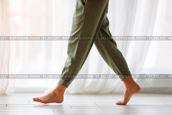 Close up focus on young female feet walking barefoot on clean tile floor at home. Young woman standing on warm floor indoors, underfloor heating concept. Woman's legs in bathroom. Floor heating. Стоковое AI-изображение, AI-художник Марина Демидюк / Фотобанк Лори