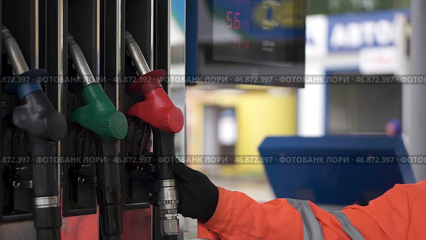 Close-up of a men's hand using a fuel nozzle at a gas station. Стоковое фото, фотограф David Kashakhi / Фотобанк Лори