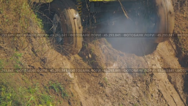 Close-up of a muddy SUV stuck on a steep slope. The wheels with aggressive tread are tugging, scattering the ground. Water is dripping off the car. Slow motion. Стоковое видео, видеограф Воловодов Владимир / Фотобанк Лори